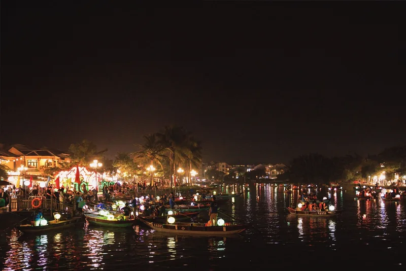 Những chiếc thuyền đèn lồng rực rỡ trôi trên sông Hoài An về đêm, phản chiếu ánh sáng xuống mặt nước.