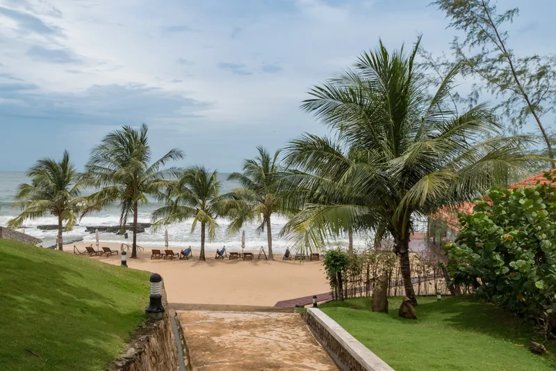Con đường rợp bóng dừa dẫn xuống bãi biển cát với ghế nằm ở Phú Quốc, Việt Nam.